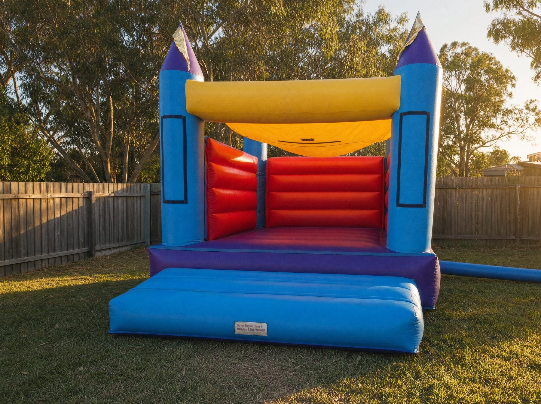 Landscape view of the 14ft Open Banner Jumping Castle in a backyard