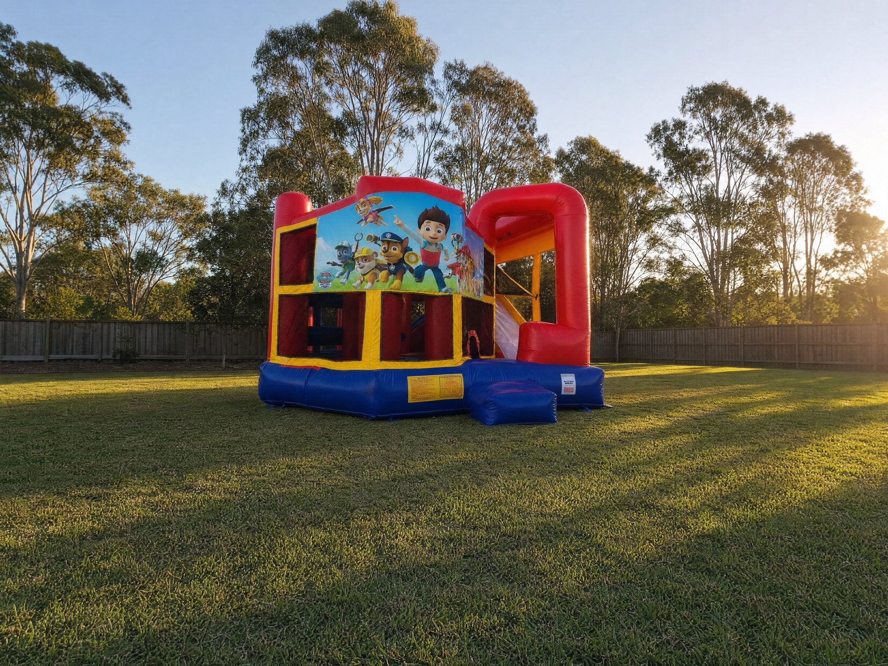 Wide landscape view of the 5in1 Banner Castle Combo showing yard scale (shown with the Paw Patrol banner, choose your theme at booking)