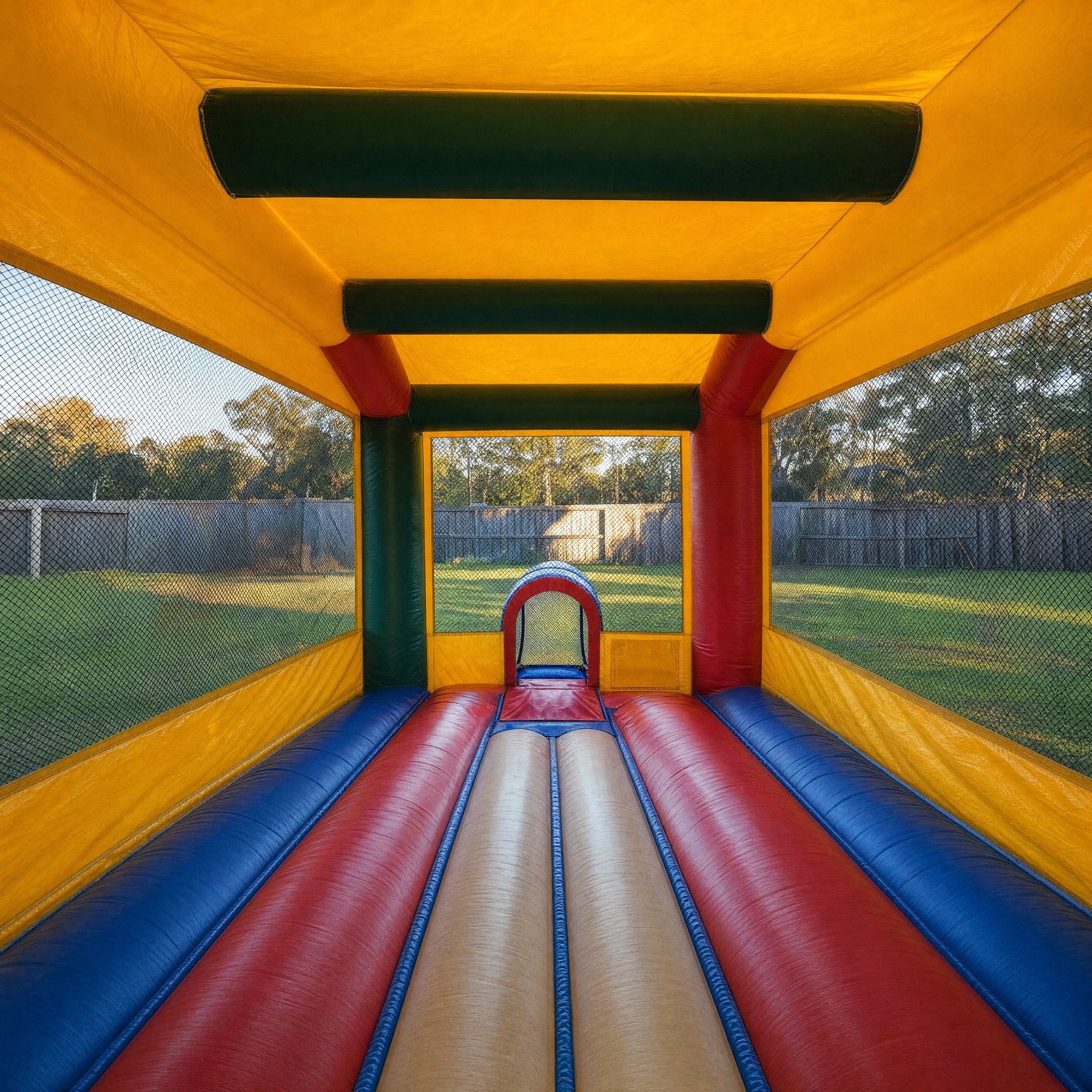 Interior of an adult jumping castle showing red, blue and cream padded floor bolsters