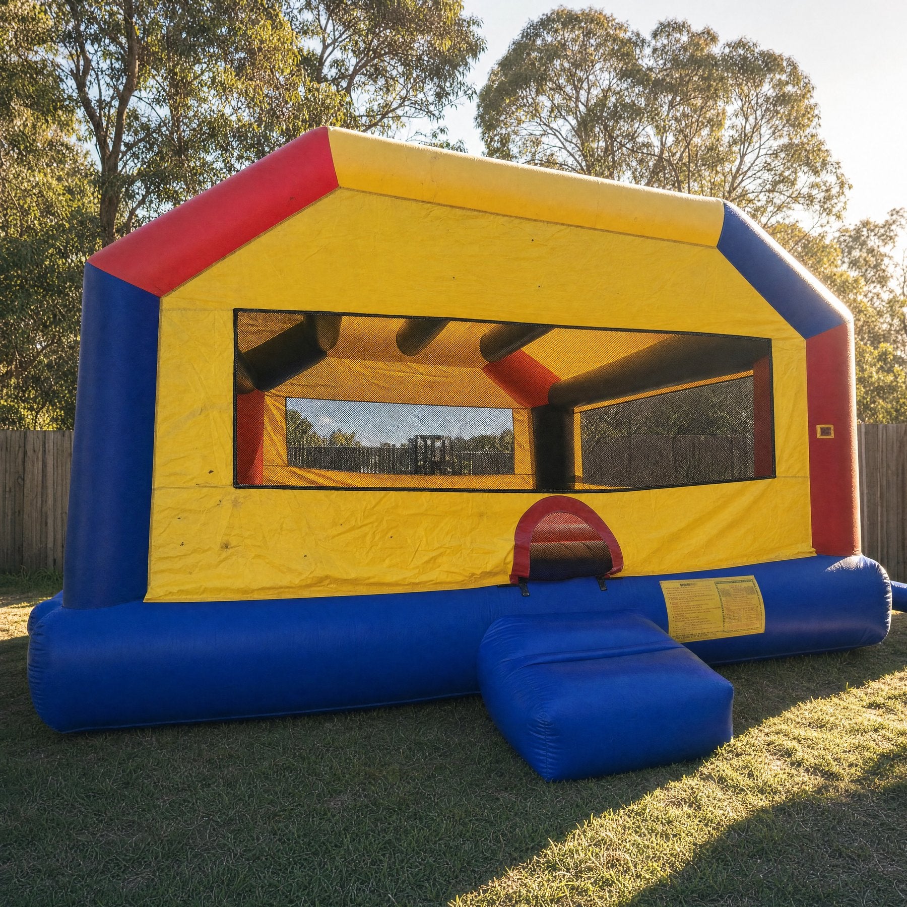 Straight-on front view of a yellow and red adult jumping castle with a large mesh window