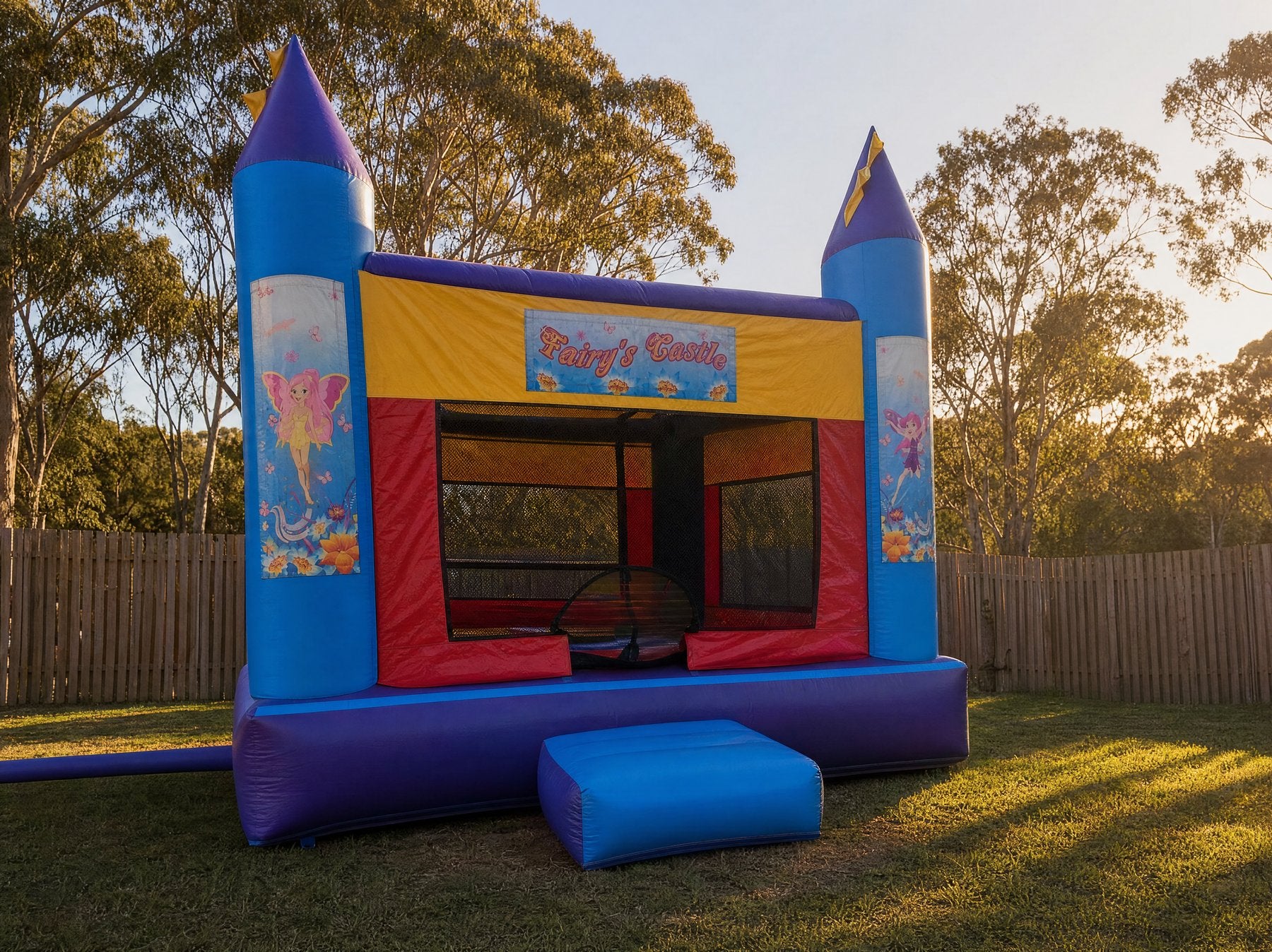 Wide low-angle view of an AM Banner jumping castle filling a backyard lawn