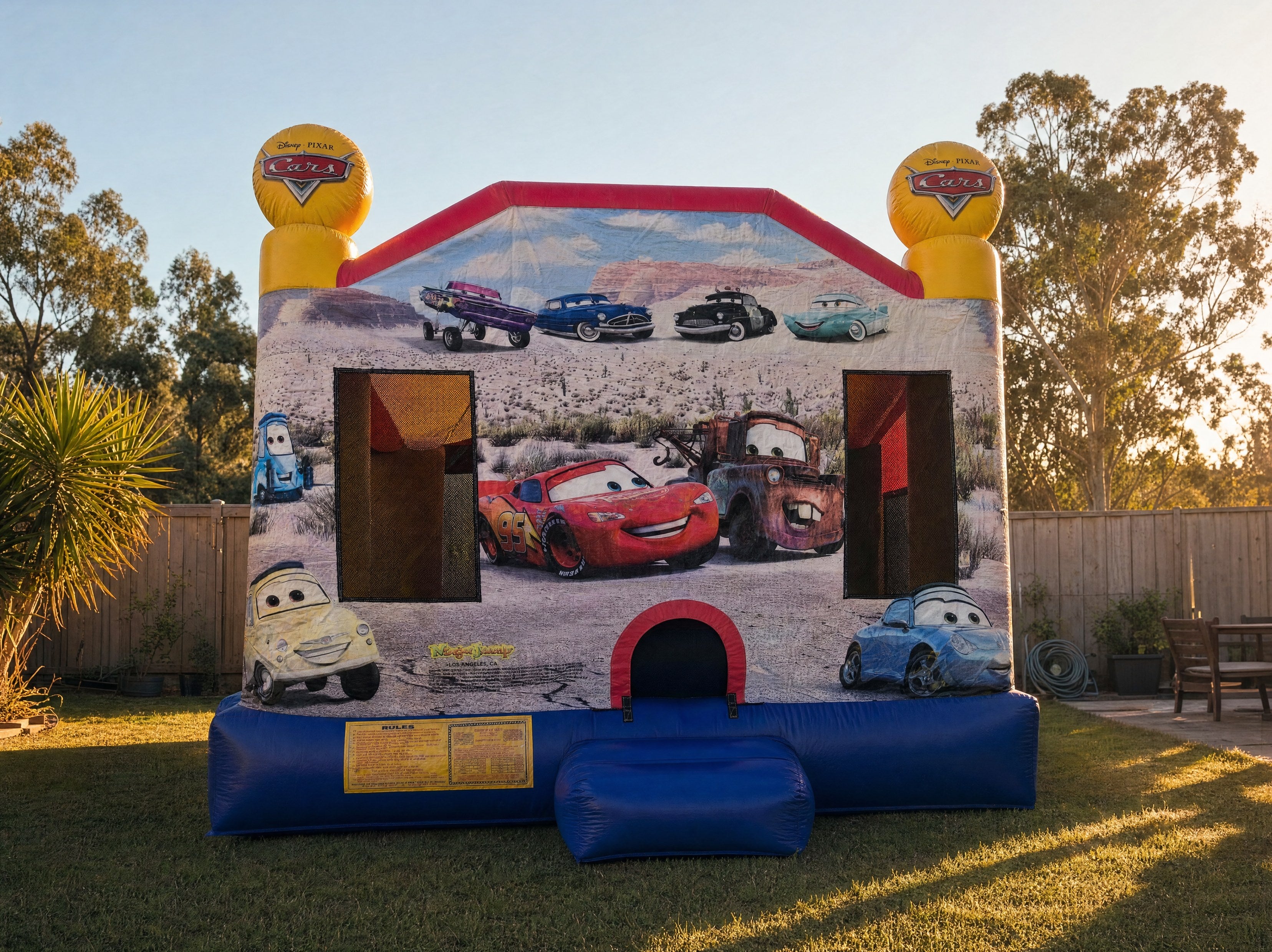 Wide front view of the Cars C4 Combo jumping castle in a Central Coast backyard at golden hour