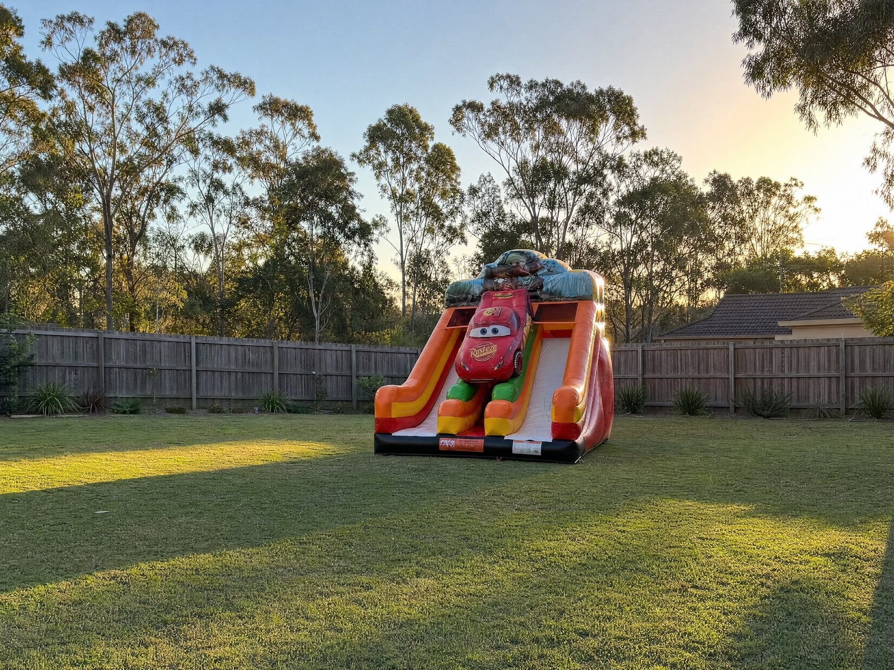 Cars Double Lane Dry Slide Hire - pulled-back backyard view showing the slide at true size