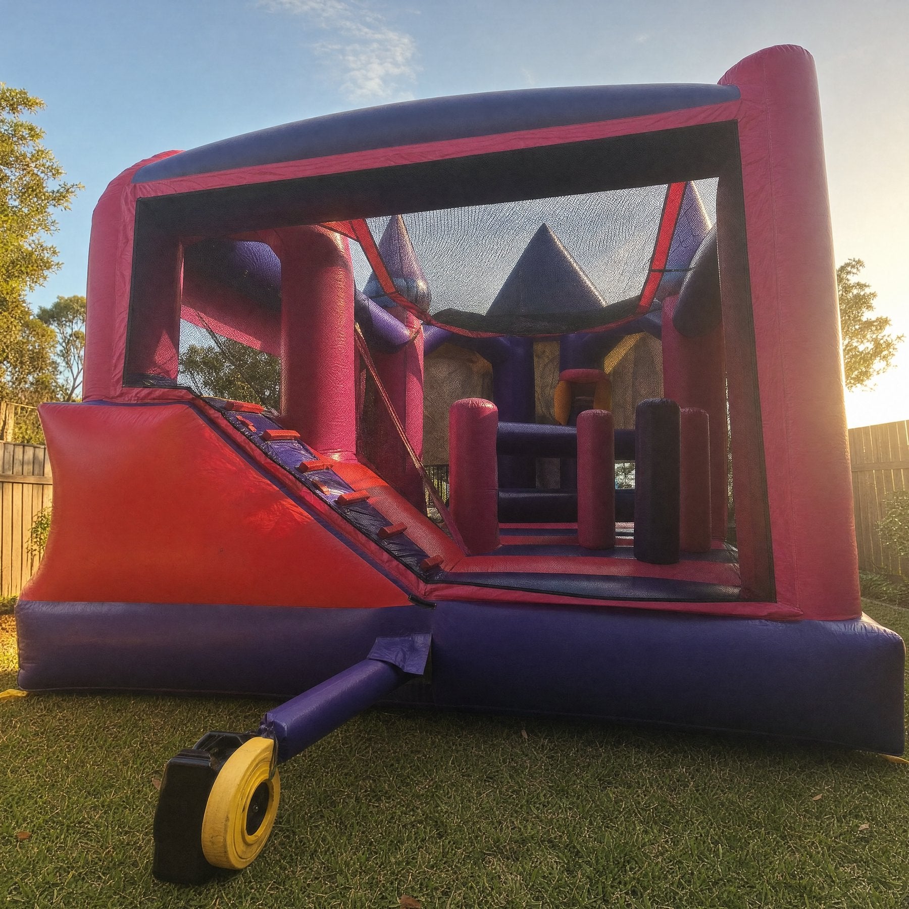 Wide rear view of a large Disney Princess combo castle filling a backyard