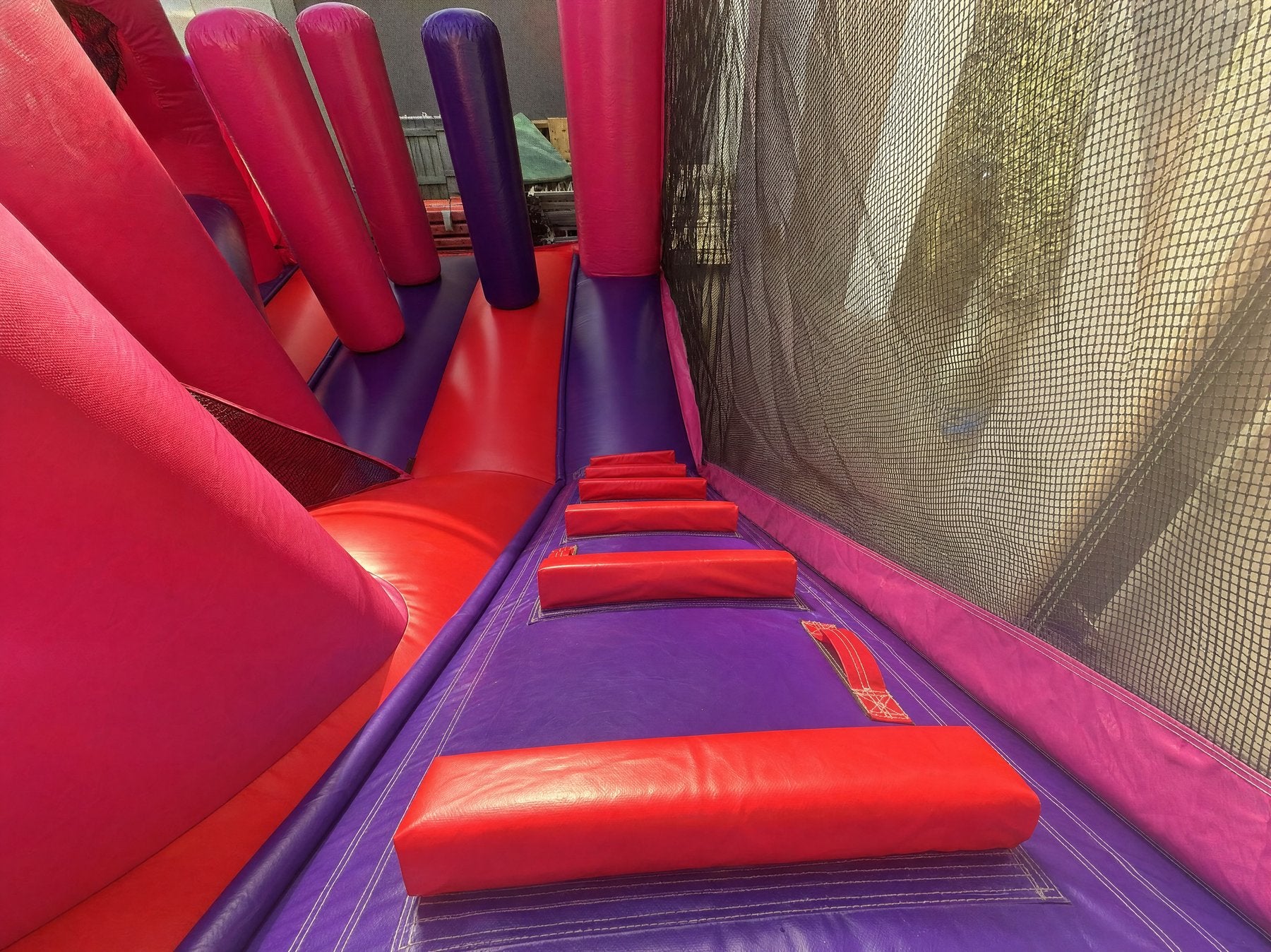 Wide interior detail of a combo castle obstacle lane with red foam pads