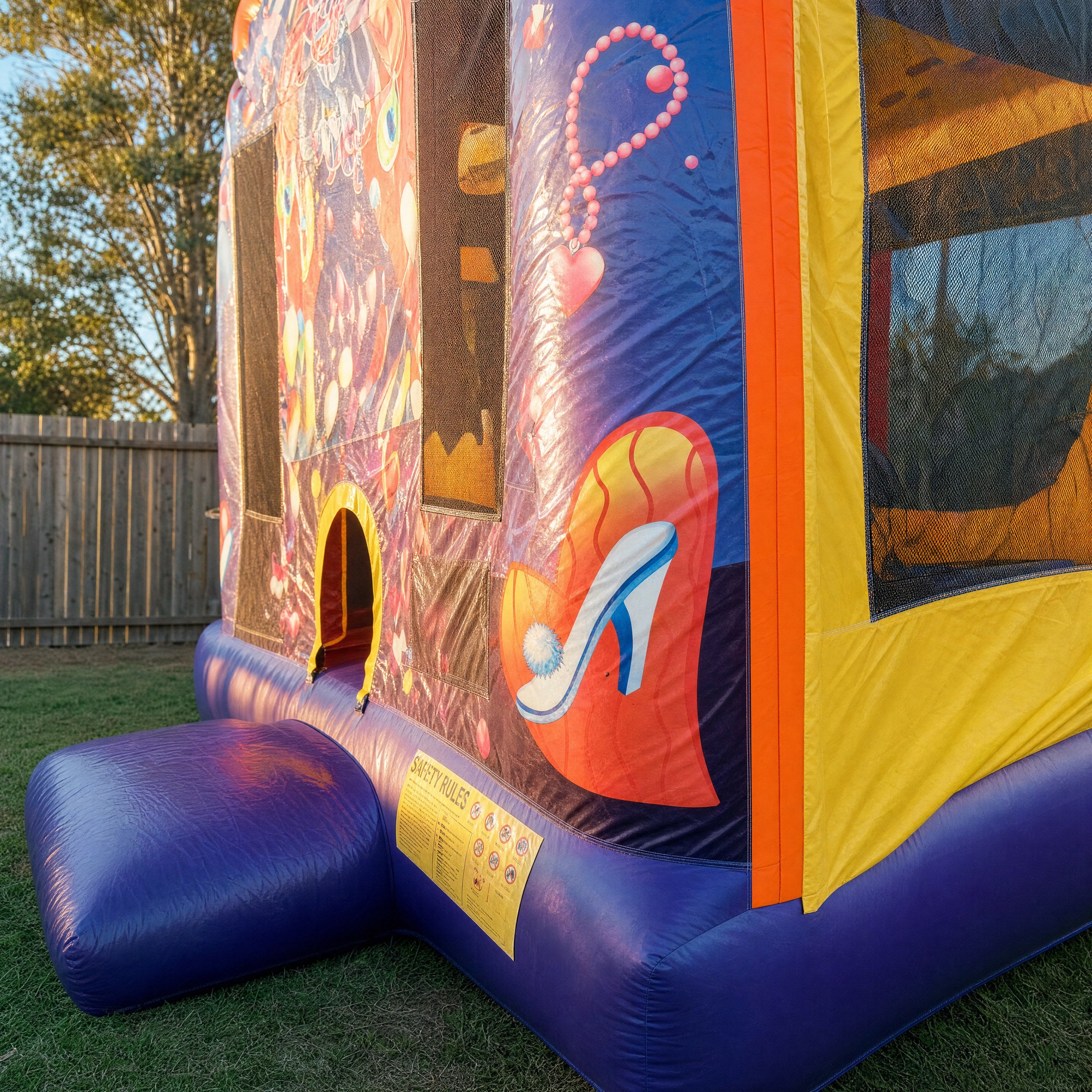 Close view of a jumping castle entrance panel with heart and shoe artwork and safety placard
