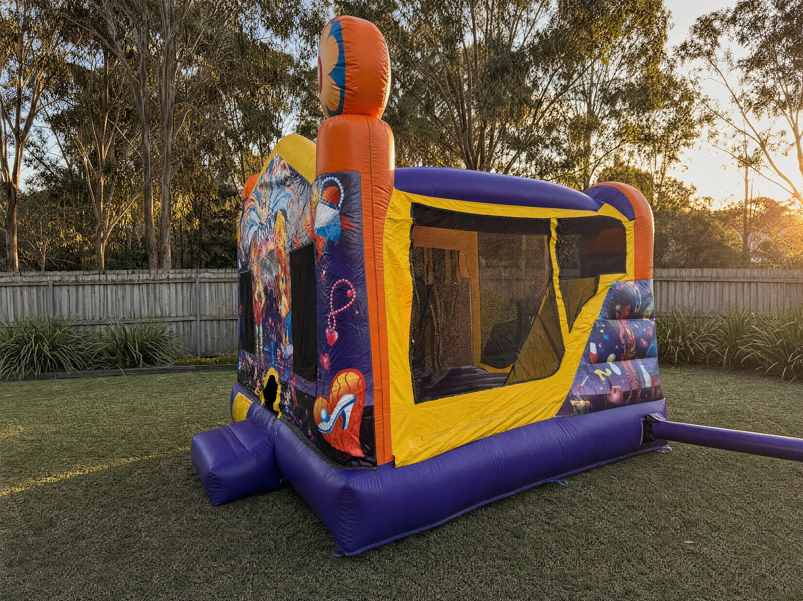 Wide side and rear angle view of a jumping castle combo showing yard depth