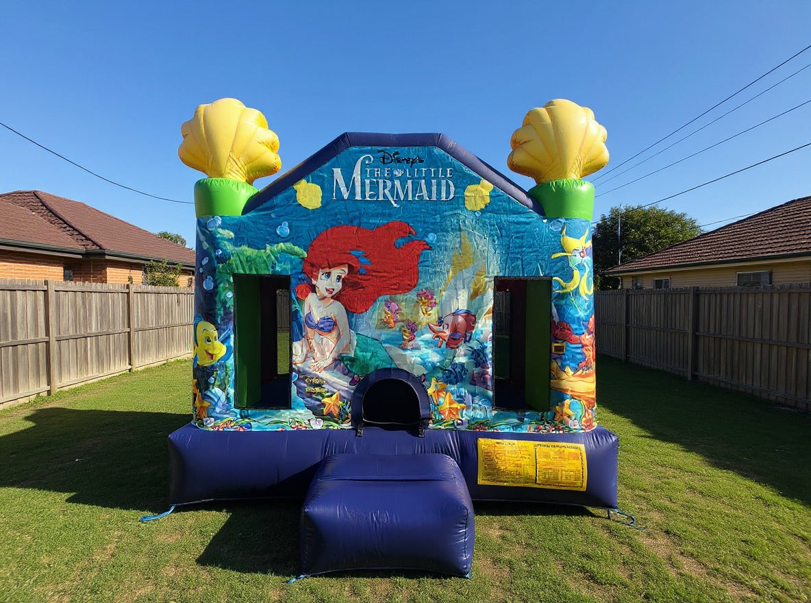 Little Mermaid Jumping Castle - wide off-centre yard view with fence and trees