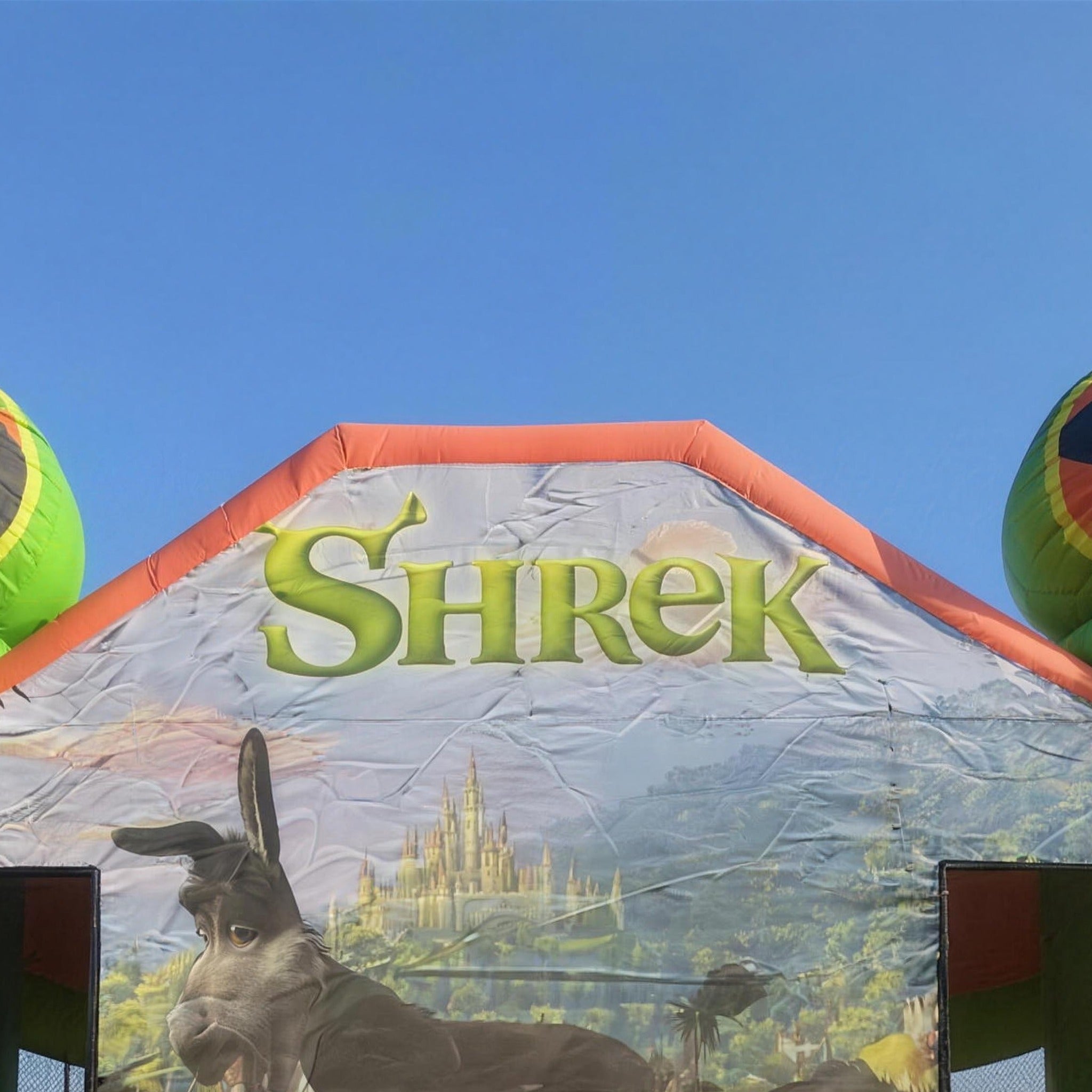 Shrek Jumping Castle Shrek and Fiona head toppers against blue sky