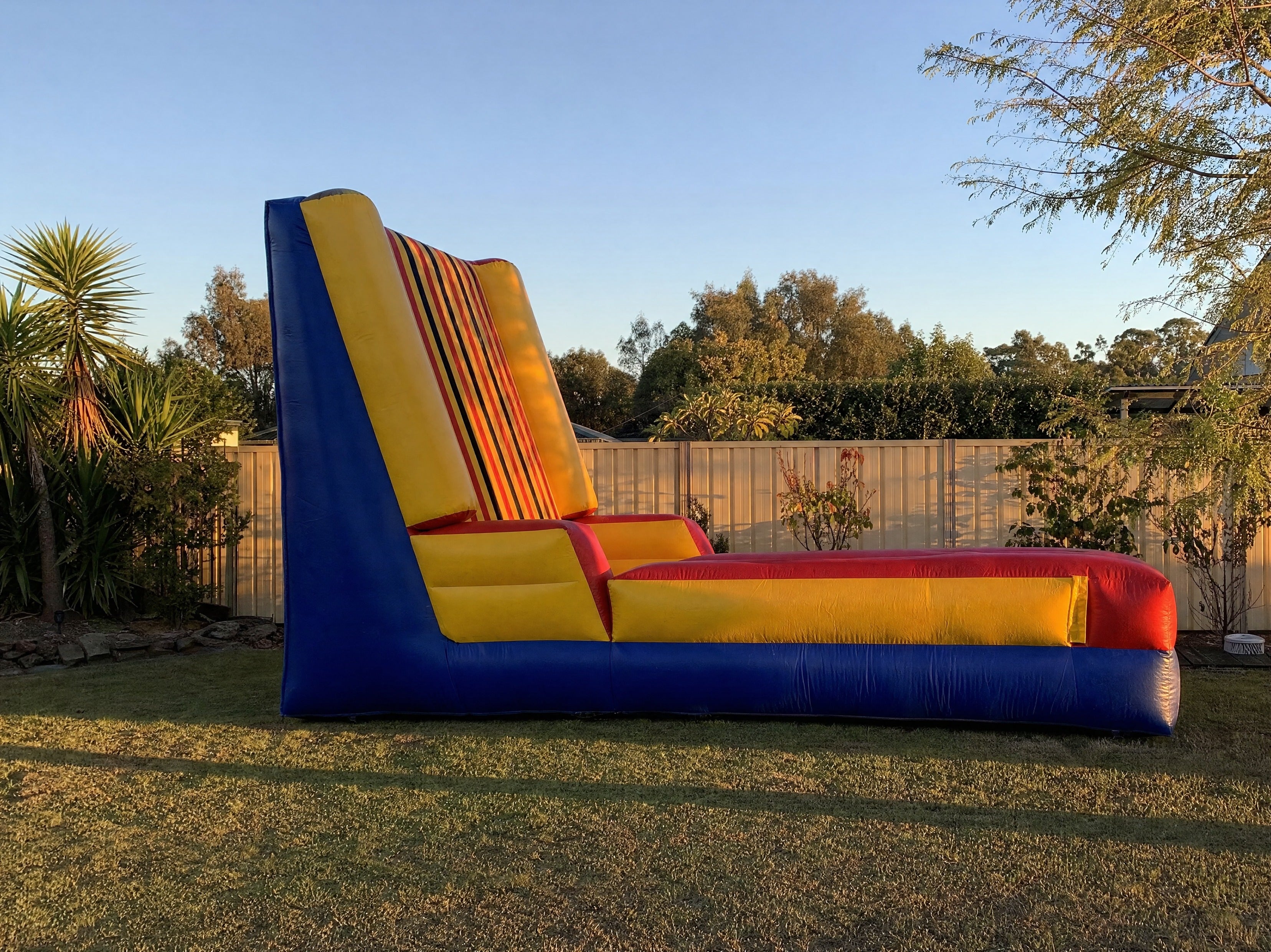 Side view of the tall Sticky Wall inflatable showing its full height in a backyard