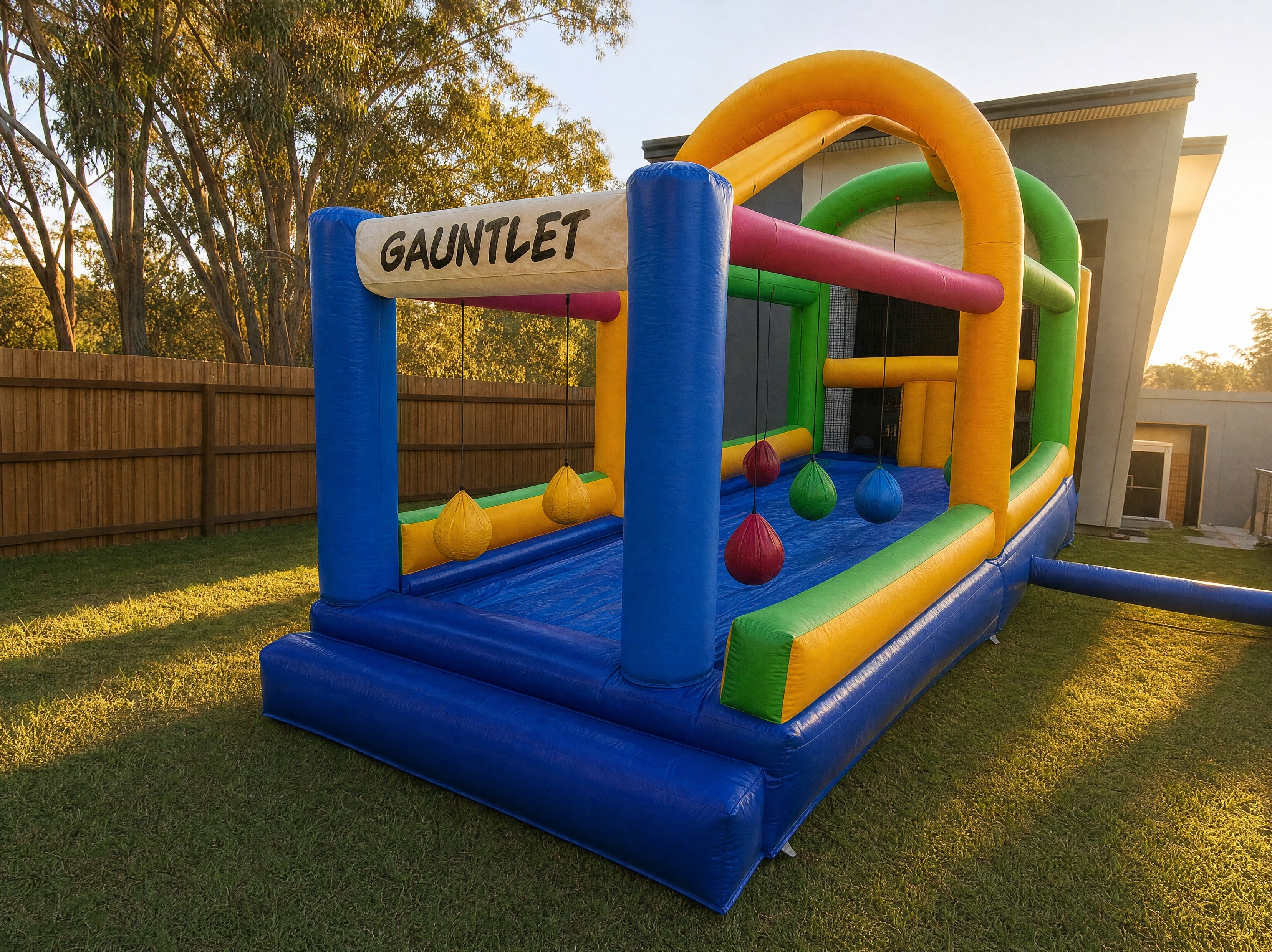 Wide side angle of The Gauntlet inflatable obstacle course showing depth in a backyard