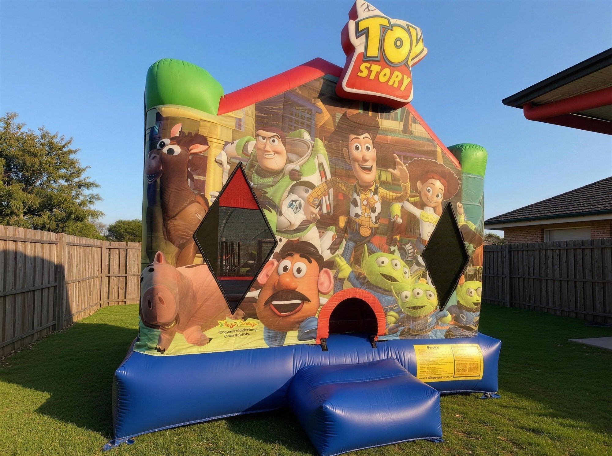 Toy Story Jumping Castle Hire in a Central Coast backyard with timber fence, Jump About party hire