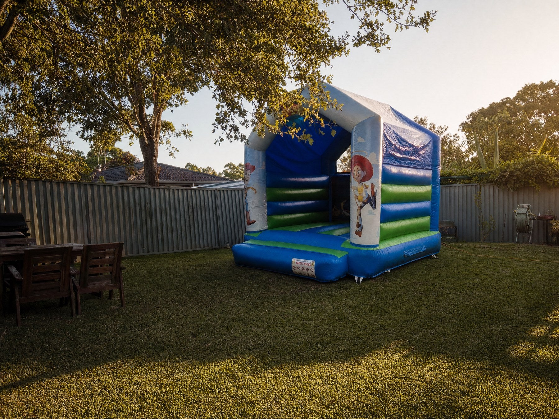 Toy Story jumping castle shown at true scale in a suburban backyard with garden furniture