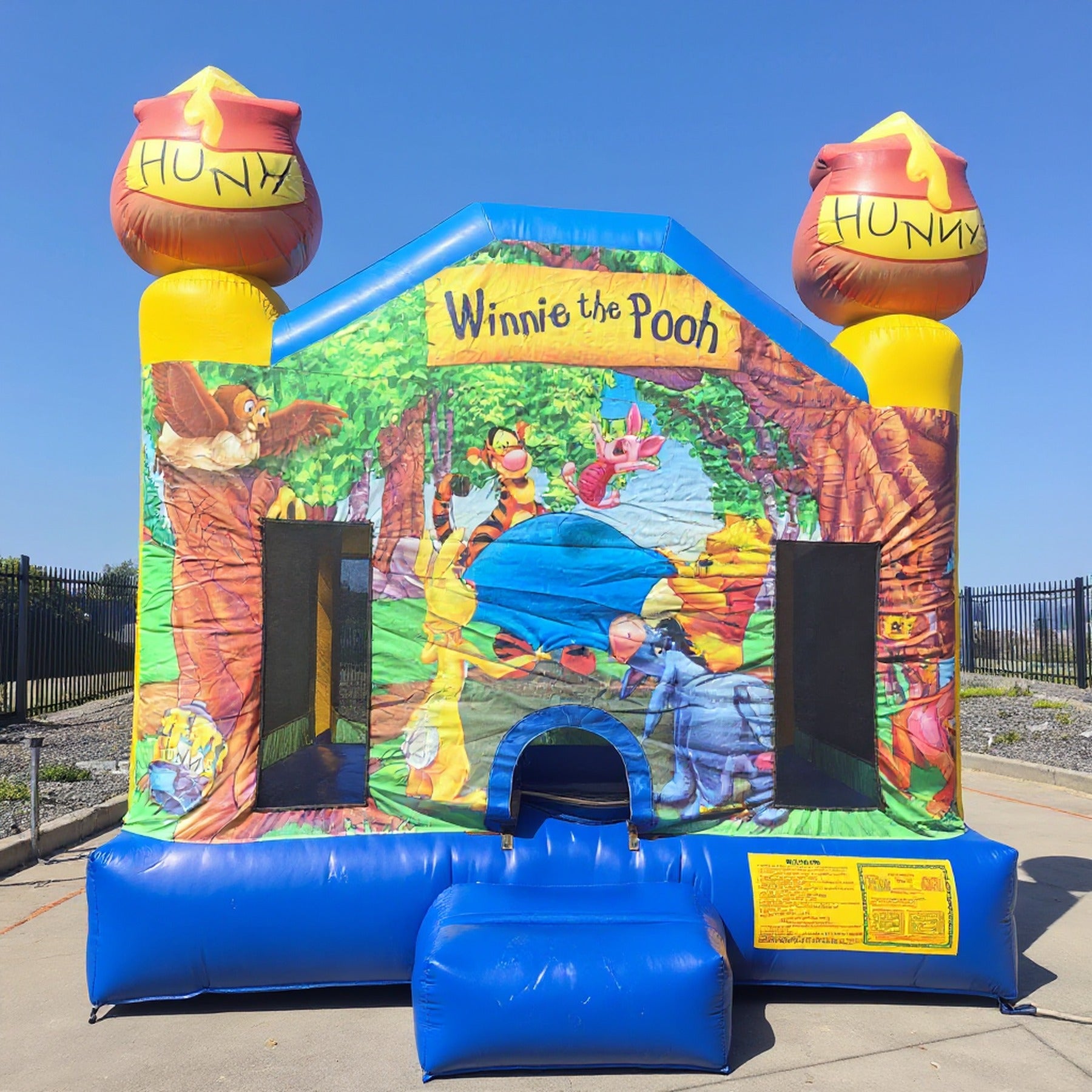 Front view of the Winnie the Pooh inflatable jumping castle with honey pot toppers