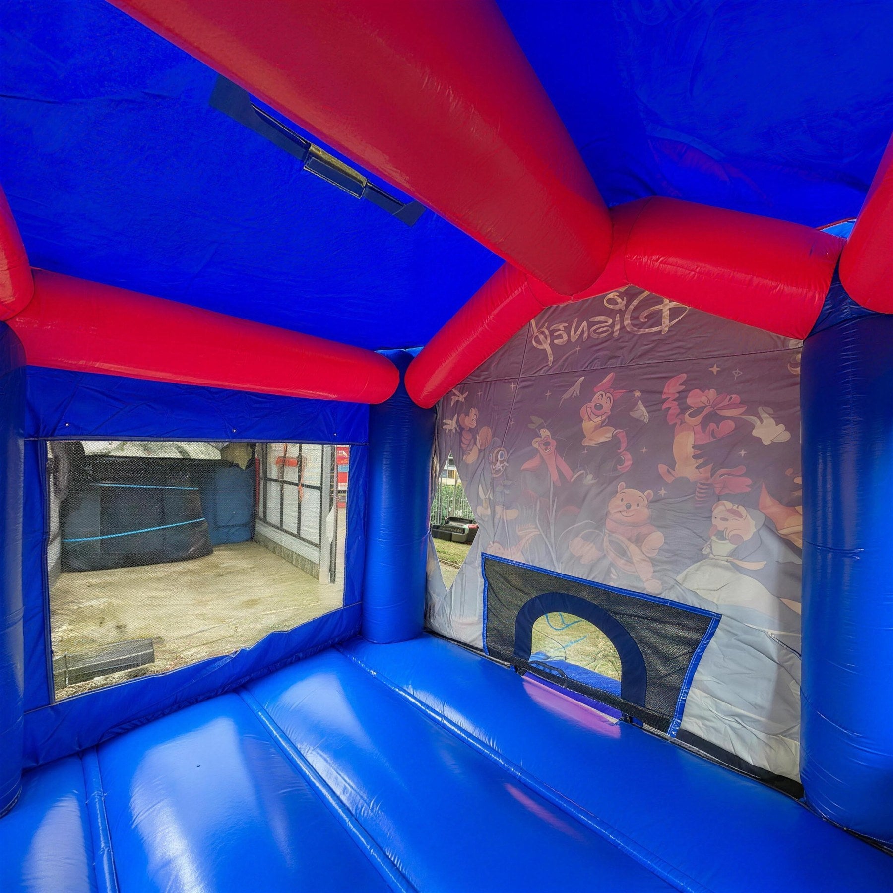 Interior view through the doorway of the World of Disney jumping castle showing the character mural